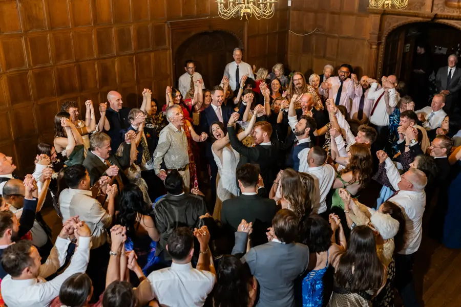 A wedding party dancing in a wood-panelled great hall